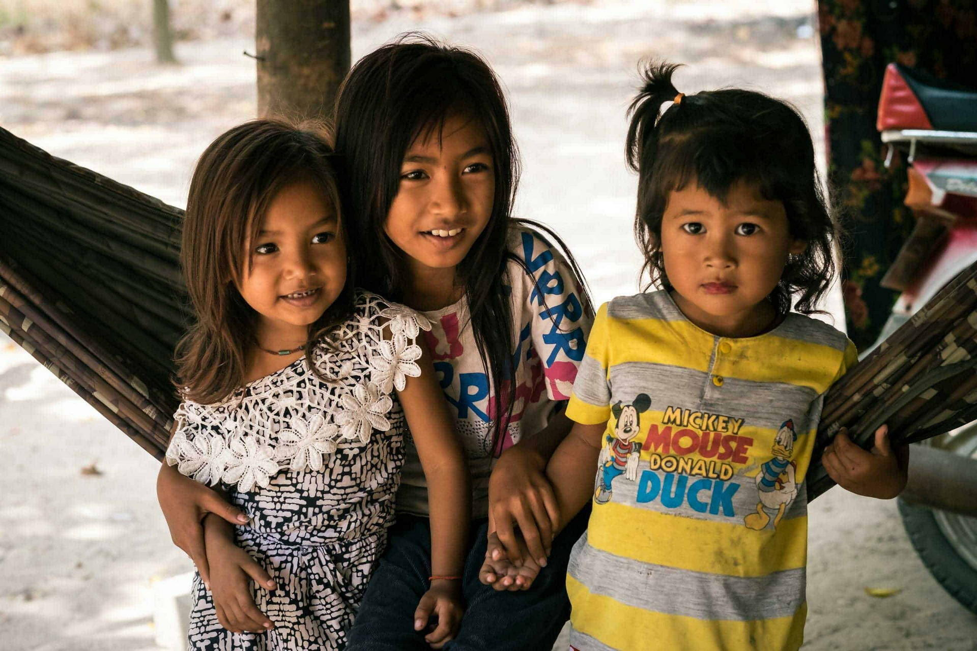 A group of foster siblings sit together on a hammock in rural Cambodia