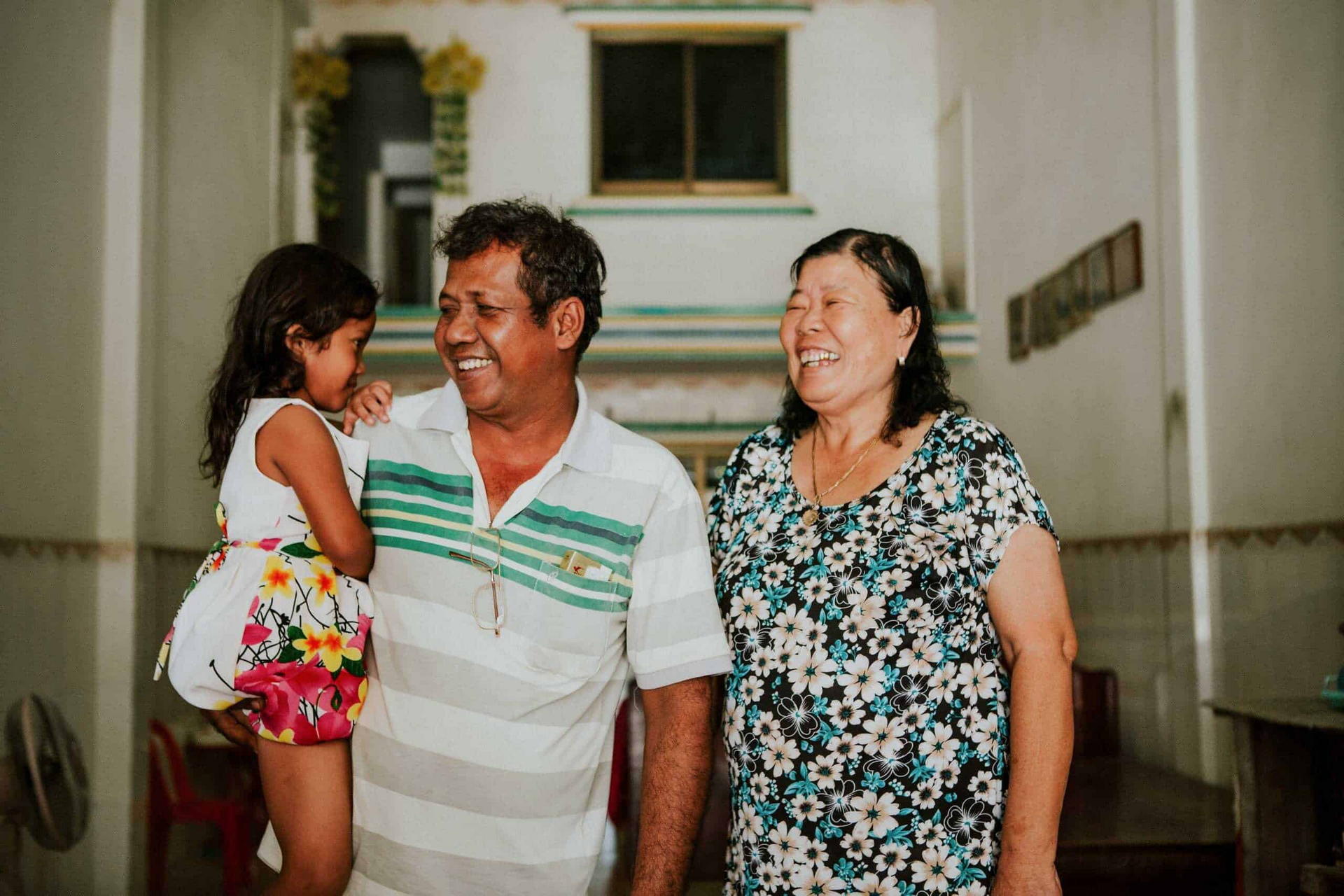 A young girl laughs with her Children in Families foster parents