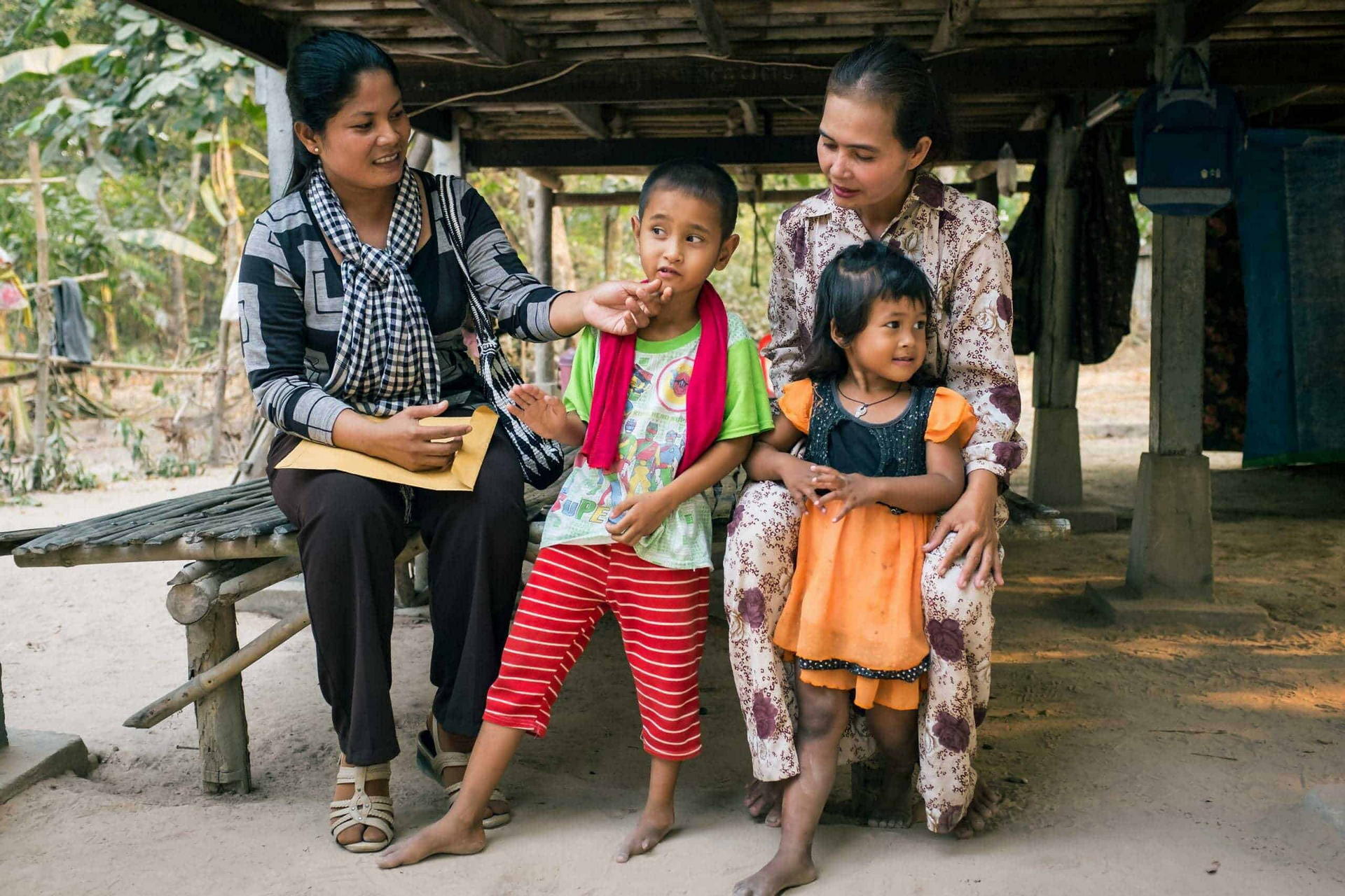 children in families foster family sitting outside in rural cambodia talking to their social worker